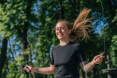 Spor salonunun portresi. Sabahları gülümseyen genç sporcu kız. Spor atlama ipi yapıyor.