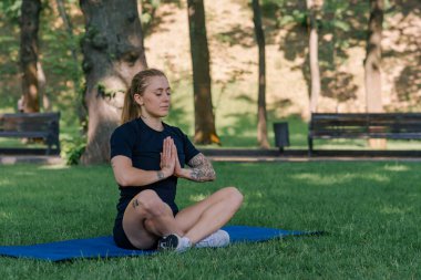 Spor yapan genç kızın portresi. Spor minderinde yoga yaparken park sağlıklı yaşam tarzı kavramını geliştiriyor.