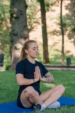 Spor yapan genç kızın portresi. Spor minderinde yoga yaparken park sağlıklı yaşam tarzı kavramını geliştiriyor.