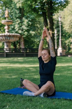 Spor yapan genç kızın portresi. Spor minderinde yoga yaparken park sağlıklı yaşam tarzı kavramını geliştiriyor.