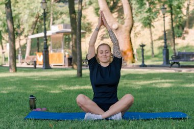 Spor yapan genç kızın portresi. Spor minderinde yoga yaparken park sağlıklı yaşam tarzı kavramını geliştiriyor.