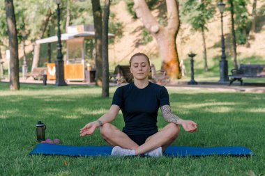 Spor yapan genç kızın portresi. Spor minderinde yoga yaparken park sağlıklı yaşam tarzı kavramını geliştiriyor.