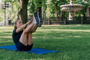 Parktaki sağlıklı yaşam tarzı konseptinde egzersiz yaparken spor minderinde karın egzersizi yapan genç bir kızın portresi.