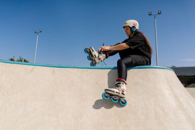 Genç hippi kız koruyucu miğferli, patenli, paten kayan, paten kayan sokak sporu yapmadan önce paten yapan.