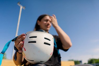 Paten yapmaya başlamadan önce kaykay parkında arka planda genç konsantre bir hippi kızın portresi güvenlik kaskını takıyor.