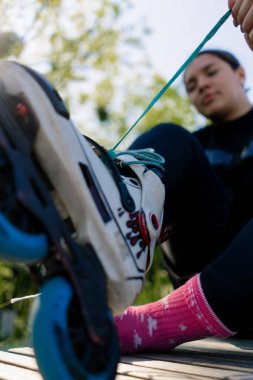 Kaykay parkında paten giyen genç hippi kız kaykay yapmadan önce bağcıklarını bağlıyor.