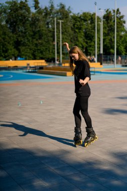 Sportif kız şehir arka planında paten üzerinde paten numarası yapıyor. Paten derslerinin keyfini çıkarıyor. Cipsler yakın sokak sporları konseptiyle.