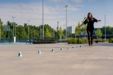 Sportif kız şehir arka planında paten üzerinde paten numarası yapıyor. Paten derslerinin keyfini çıkarıyor. Cipsler yakın sokak sporları konseptiyle.