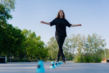 Sportif kız şehir arka planında paten üzerinde paten numarası yapıyor. Paten derslerinin keyfini çıkarıyor. Cipsler yakın sokak sporları konseptiyle.