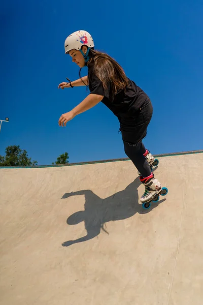 若い熟練した女性ローラーブレーディングとスケートパークのランプにジャンプ彼女のトリックやローラーブレーディング競技の技術を実践 — ストック写真