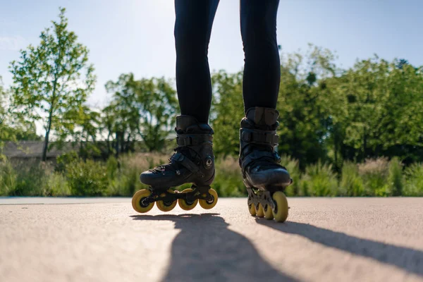 在公园城市背景下练习轮滑技巧的女运动员喜欢轮滑课近腿街头运动 — 图库照片