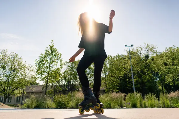 スポーティガールは 街の背景に公園でローラースケートに乗ります アクティブガールは ローラースケートレッスンストリートスポーツコンセプトを楽しんでいます — ストック写真