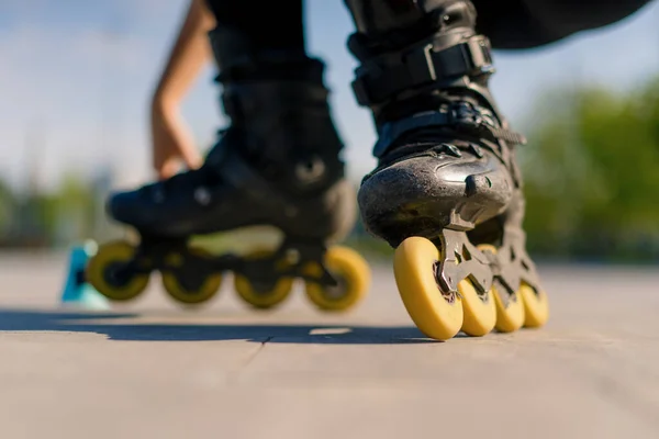 スポーティガールは 街の背景に公園でローラースケートのトリックを実践し チップクローズアップストリートスポーツコンセプトでローラースケートレッスンを楽しむ — ストック写真