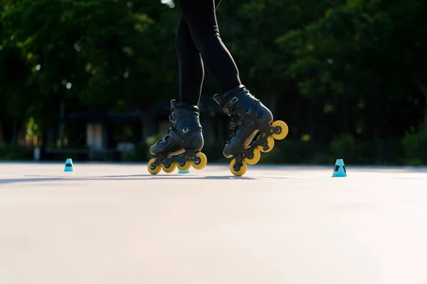 スポーティガールは 街の背景に公園でローラースケートのトリックを実践し チップクローズアップストリートスポーツコンセプトでローラースケートレッスンを楽しむ — ストック写真