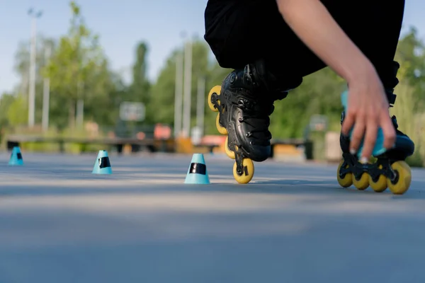 スポーティガールは 街の背景に公園でローラースケートのトリックを実践し ストリートスポーツのチップクローズアップでローラースケートレッスンを楽しみます — ストック写真