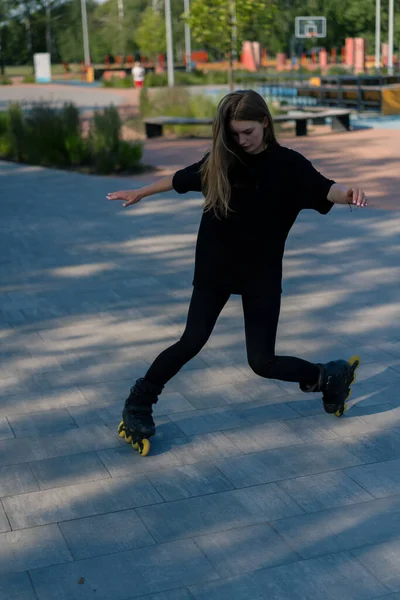 スポーティガールは 街の背景に公園でローラースケートに乗ります アクティブガールは ローラースケートレッスンストリートスポーツコンセプトを楽しんでいます — ストック写真