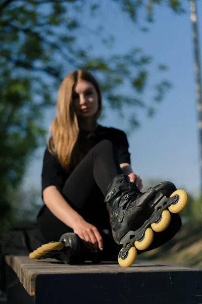 若い女の子は 大きなホイールクローバーのローラースケートをトレーニングする前に ローラースケートの公園に座っています — ストック写真