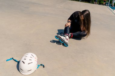 Sinirli kız paten kayarken koruyucu kask asfalt aktif eğlence pateni hobisi fırlatıyor.