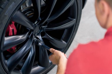 Otomotiv tamircisi, lüks beyaz bir arabanın tekerleğini değiştiriyor. Yakından çekilen bir araba servisinde balon anahtarı kullanıyor.