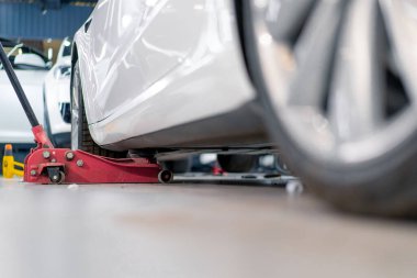 Beyaz lüks araba temizleme ve kuru temizleme sırasında kırmızı tekerlekli kriko ile kaldırılıyor.