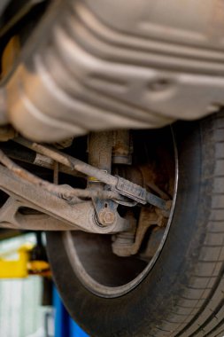 Lüks bir arabanın sağ arka tekerinin kaldıracına yakın çekim. Aşağıdan araba servisi manzarası var.