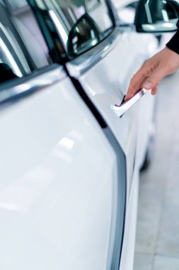 Bir adam araba servisinde kuru temizleme ve temizlik yaptıktan sonra lüks beyaz arabasının kapısını açar.