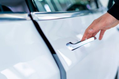 Bir adam araba servisinde kuru temizleme ve temizlik yaptıktan sonra lüks beyaz arabasının kapısını açar.