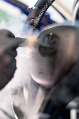 Bir oto yıkama işçisi lüks bir arabanın içini dikkatlice temizler. Bir bez parçasıyla. Bir elektrikli süpürgeyle.