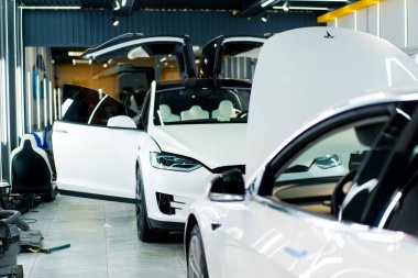 Bir araba servisinde ya da otoparkta yıkama ve kuru temizleme yaptıktan sonra açık kapısı olan lüks beyaz bir arabanın aynasını ve farını detaylandırmak.