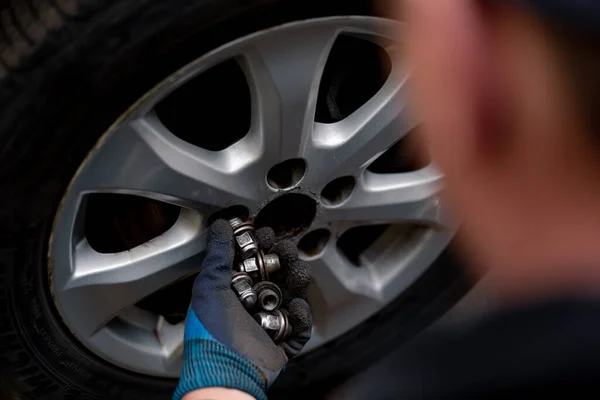 汽车修理工在街上的轮胎车间里用钻头把一辆黑色汽车的轮子换掉 详细说明汽车修理的情况 — 图库照片