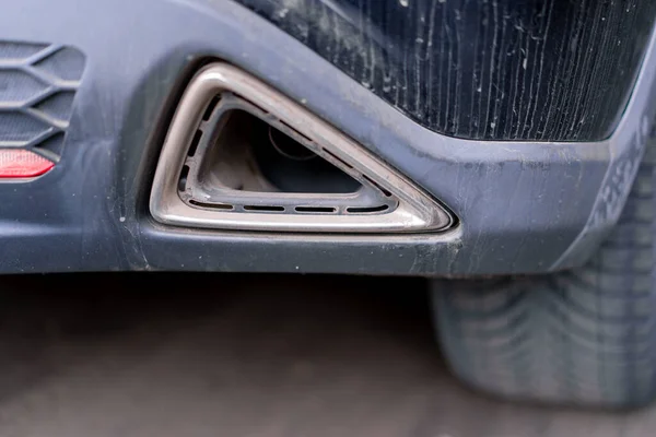 Automotive exhaust pipe or tailpipe tip Standing nondescript car close-up view from low angle in real time without people