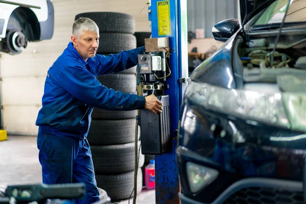Male Car Service Worker Lifts Luxury Black Car Blue Lift — Stock Photo, Image