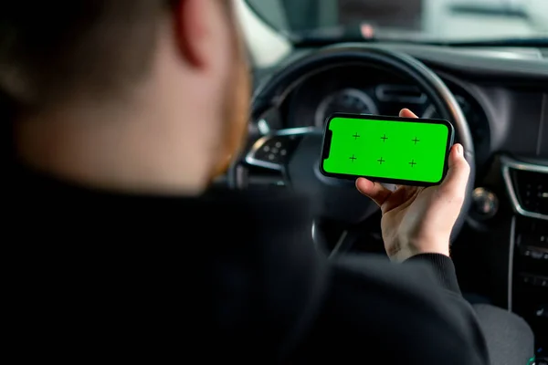 男は彼の手に緑のスクリーン携帯電話で高級車に座っています — ストック写真
