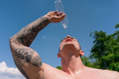 Genç sporcu vücut geliştirici spor sahasında su sıçratıyor sokak antrenmanlarından sonra su sıçrıyor güzel, seksi, şişkin vücut.