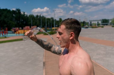 Genç sporcu vücut geliştirici spor sahasında su sıçratıyor sokak antrenmanlarından sonra su sıçrıyor güzel, seksi, şişkin vücut.