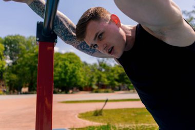 Yatay paralel barlarda spor yaptıktan sonra terli genç bir sporcunun portresi.