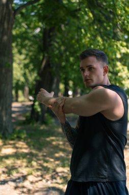 Dövmeleri olan genç bir sporcunun portresi. Açık hava sokak eğitimleri yapıyor. Park motivasyonu üzerine.