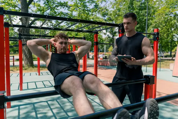 Fitness Trenér Tabletem Ruce Trénuje Mladého Sportovce Pumpování Jeho Břicha — Stock fotografie