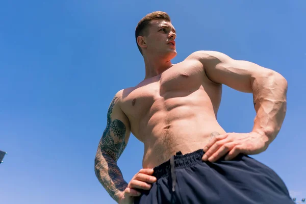 young sportsman bodybuilder standing on sports field outdoor workout beautiful sexy pumped body abs closeup