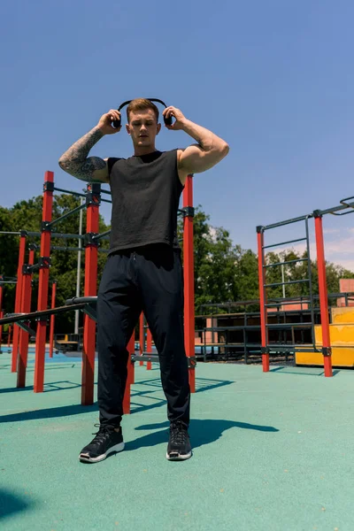一名汗流浃背的年轻运动员的肖像 他戴着耳机 身上有纹身和穿孔 带着公园动机的户外训练 — 图库照片