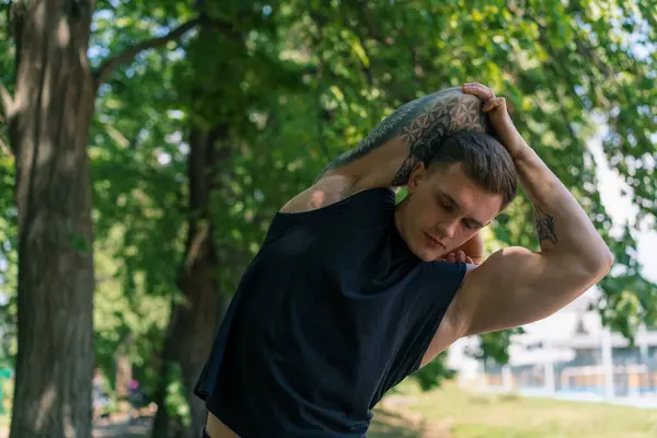 公園の動機で屋外のストリートトレーニングを行っているタトゥーを持つ若いスポーツマンの肖像画 — ストック写真