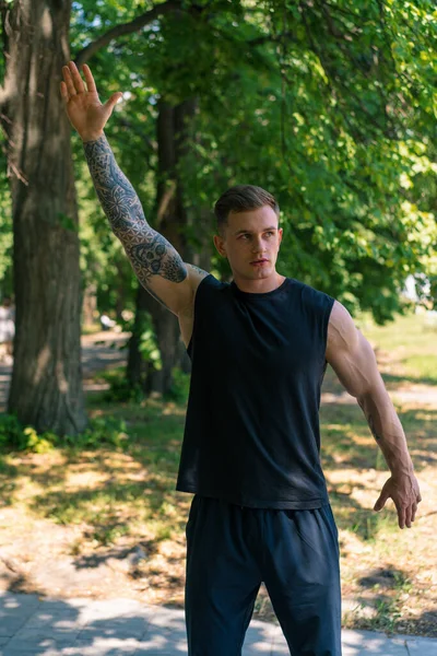 公園の動機で屋外のストリートトレーニングを行っているタトゥーを持つ若いスポーツマンの肖像画 — ストック写真