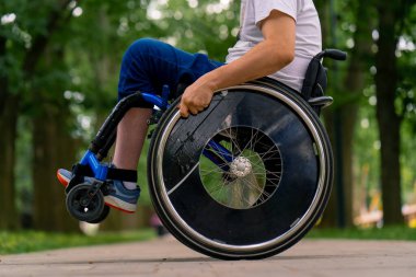 Özürlü bir adam şehir parkında ağaçlara karşı tekerlekli sandalye dublörlüğü yapar.