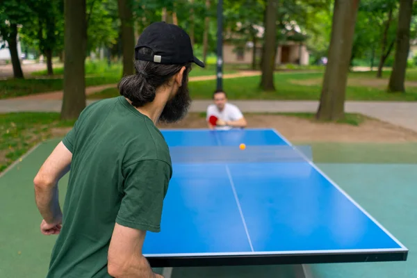 包容的老人在城市公园与坐在轮椅上的残疾人打乒乓球 — 图库照片
