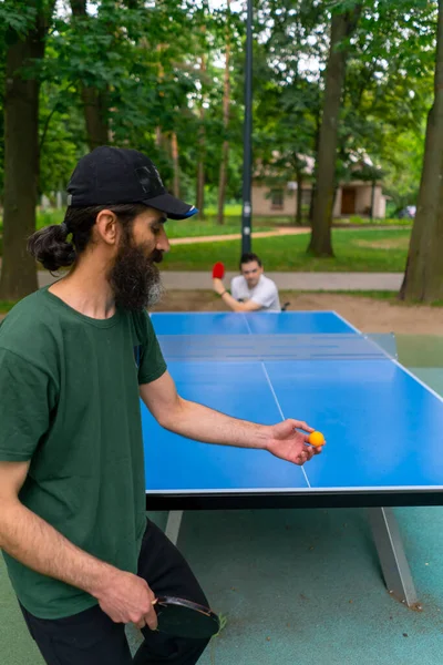 包容的老人在城市公园与坐在轮椅上的残疾人打乒乓球 — 图库照片