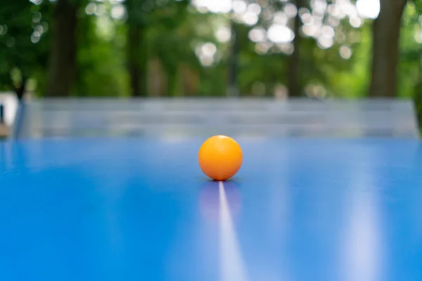 Oranžový Tenisový Míček Spočívá Modrém Tenisovém Stole Vedle Sítě Městském — Stock fotografie