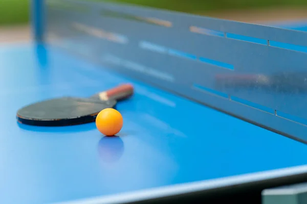Tenisová Raketa Oranžový Tenisový Míček Leží Modrém Tenisovém Stole Vedle — Stock fotografie