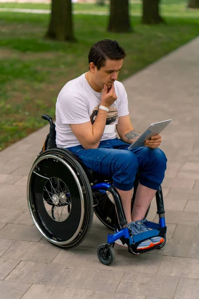 Inkluzywność Mężczyzna Niepełnosprawny Wózku Wpatruje Się Uważnie Tablet Który Trzyma — Zdjęcie stockowe