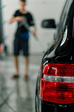 Oto yıkamada temizlik ve kuru temizlemeden sonra lüks siyah bir arabanın arka lambasına yakın çekim.