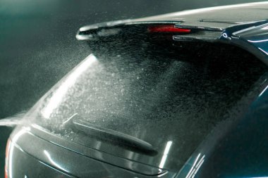 Araba yıkama kutusundaki sprey şişeden araba yıkama işlemi yapılırken siyah bir arabanın arka camını kapatın.